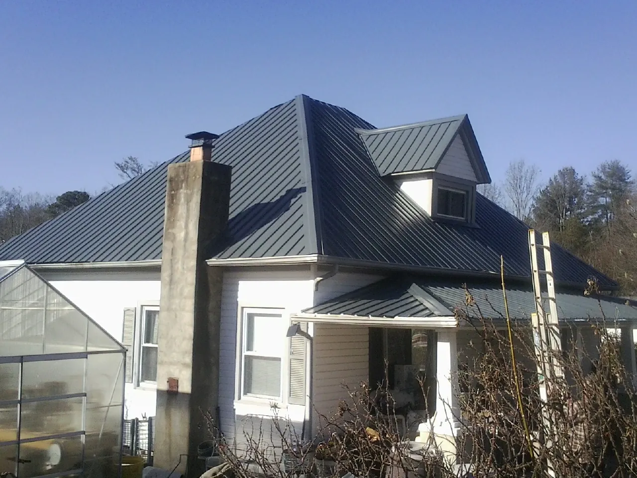 Dark blue standing seam metal roof on a white farmhouse with dormer — Slate & Tile Roof Repair by Roofing Brothers in Berwick