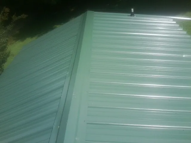 New green metal panels meeting at the ridge of a roof — Flat Roof Repair work by our crew in Berwick