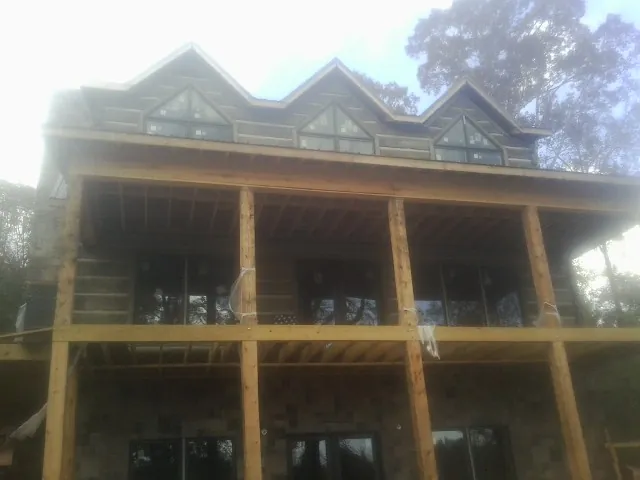 Dormers and porch framing on a large log home under construction — Roof Coating work by our crew in Berwick