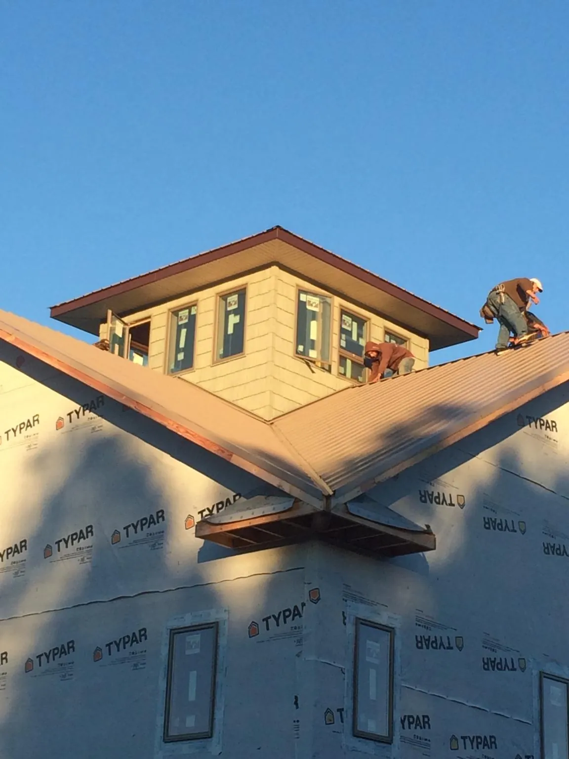 Roofers working around a rooftop cupola on a new metal roof at sunset — Roof Waterproofing in Berwick by Roofing Brothers